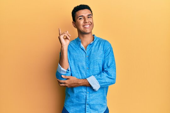 Young arab man wearing casual clothes with a big smile on face, pointing with hand and finger to the side looking at the camera.