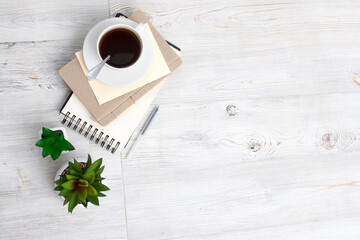 desk office with blank notepad, coffee cup and pen on wood table. Flat lay top view copy space.