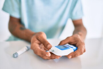 Young hispanic diabetic man measuring glucose level at home