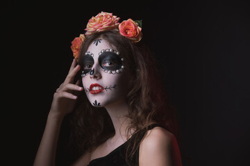 Girl with skeleton makeup and flowers in her hair on a dark background