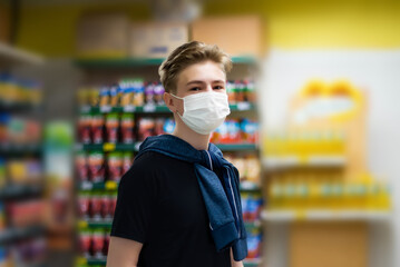Fototapeta na wymiar Boy wears protected mask in store. Shopping time during coronavirus outbreak.Boy in a medical mask. Quarantine and protection virus, flu, epidemic COVID-19. Coronavirus quarantine.