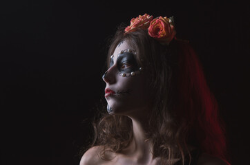 Girl with skeleton makeup and flowers in her hair on a dark background