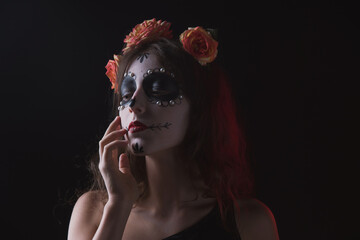 Girl with skeleton makeup and flowers in her hair on a dark background