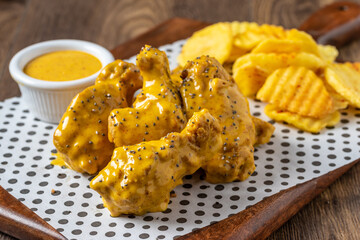 Baked chicken wings with sesame and sauce on wooden background