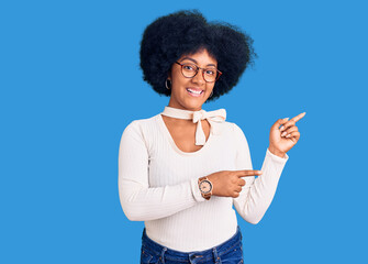 Young african american girl wearing casual clothes and glasses smiling and looking at the camera pointing with two hands and fingers to the side.