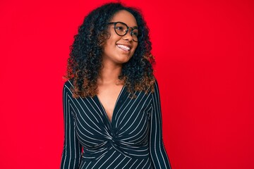 Fototapeta premium Young african american woman wearing casual clothes and glasses looking away to side with smile on face, natural expression. laughing confident.