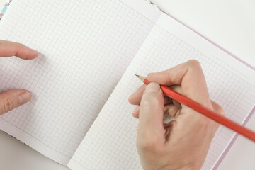 Female hands holding red pencil and writing something in a notebook, goal setting and planning concept