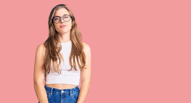 Beautiful caucasian young woman wearing casual clothes and glasses relaxed with serious expression on face. simple and natural looking at the camera.