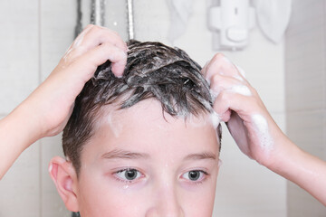 Hygienic procedures and healthy habits of a preteen boy - taking shower and washing hair with shampoo