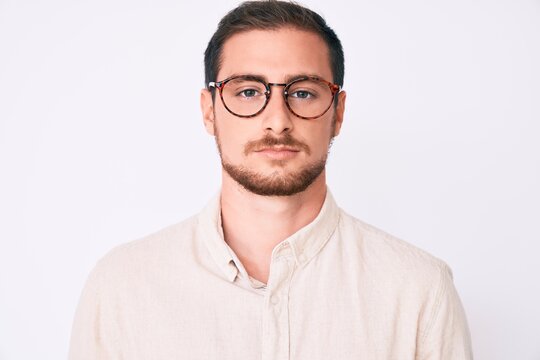 Young handsome man wearing casual clothes and glasses with serious expression on face. simple and natural looking at the camera.