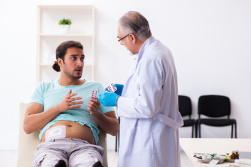 Injured young man visiting experienced male doctor