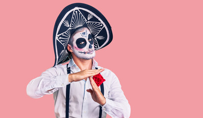 Man wearing day of the dead costume over background doing time out gesture with hands, frustrated and serious face