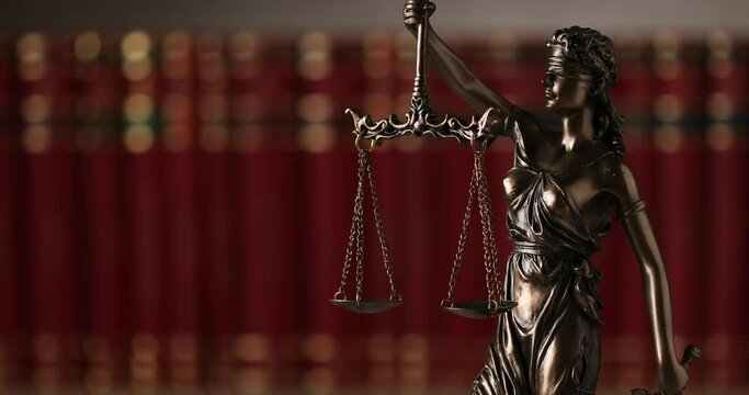 international bronze symbol of law represented by blindfolded goddess holding a balance signifying two broad sources of law, impartiality and power, spinning slowly in a university room