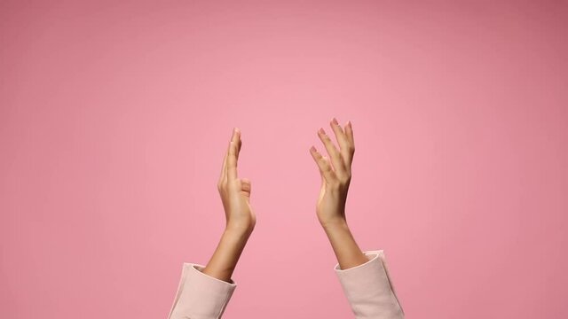 woman's hands clapping, pointing fingers and applauding on pink background