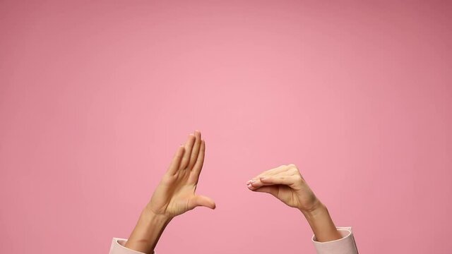 woman's hands making a gossip gesture, talking and moving on pink background