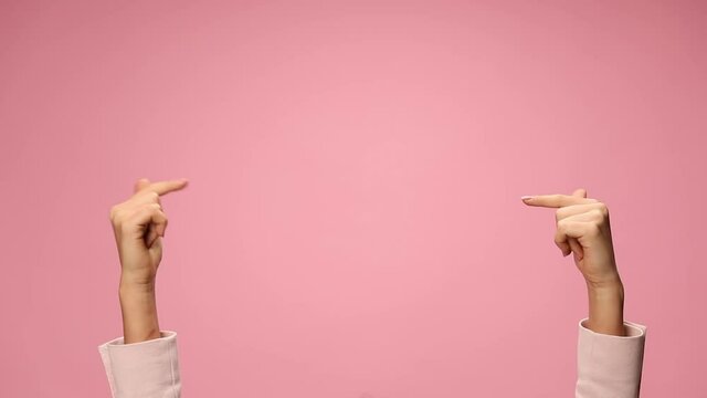 woman's hands making rock and roll gesture, pointing fingers and celebrating, making thumbs up sign and dancing on pink background