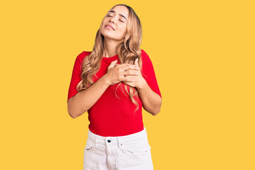 Fototapeta na wymiar Young beautiful blonde woman wearing casual clothes smiling with hands on chest with closed eyes and grateful gesture on face. health concept.
