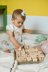 Sustainable eco-friendly safe wooden toys for baby and kids. Baby girl play with wooden blocks made with organic, renewable eco-friendly materials