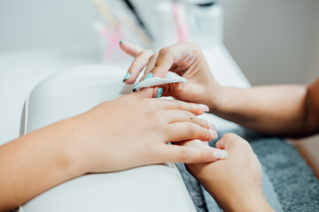 Young woman getting a beautiful manicure in the salon. The process of making nails.