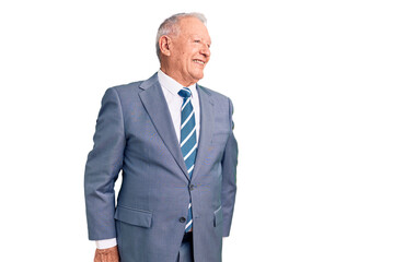 Senior handsome grey-haired man wearing elegant suit looking away to side with smile on face, natural expression. laughing confident.