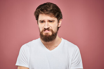 Fototapeta premium Emotional bearded man in white T-shirt discontent pink background