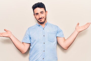 Young hispanic man wearing casual clothes clueless and confused with open arms, no idea and...