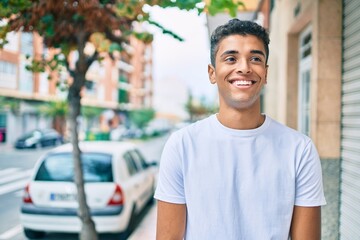 Young latin man smiling happy walking at the city.