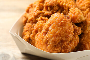 Tasty deep fried chicken pieces on wooden table, closeup