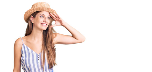 Obraz na płótnie Canvas Young beautiful blonde woman wearing summer hat very happy and smiling looking far away with hand over head. searching concept.