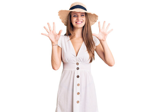Young beautiful blonde woman wearing summer dress and hat showing and pointing up with fingers number ten while smiling confident and happy.