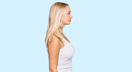 Obraz premium Young blonde girl wearing casual style with sleeveless shirt looking to side, relax profile pose with natural face and confident smile.