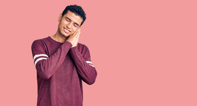 Hispanic handsome young man wearing casual clothes sleeping tired dreaming and posing with hands together while smiling with closed eyes.