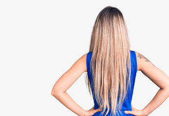 Young beautiful blonde woman wearing cheerleader uniform standing backwards looking away with arms...