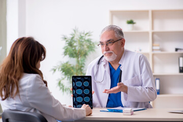 Old male doctor radiologist and his young female assistant in th