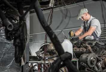 Fototapeta na wymiar Automotive Technician Repairs Vehicle Diesel Engine