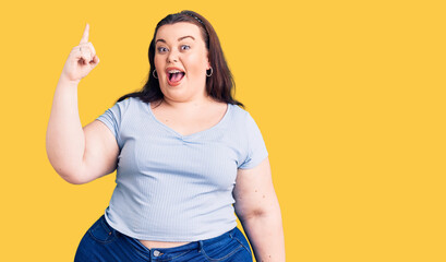 Young plus size woman wearing casual clothes pointing finger up with successful idea. exited and happy. number one.