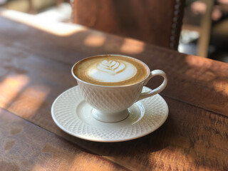 Hot cappuccino cup on wooden table in coffee shop