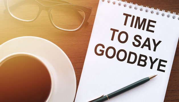 Time to say goodbye text. A concept that means a moment of separation from something. Notepad on a wooden table with a cup of coffee and glasses - Powered by Adobe