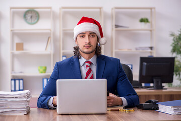 Young male employee working in the office at Christmas Eve