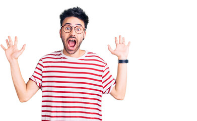 Fototapeta premium Young hispanic man wearing casual clothes celebrating crazy and amazed for success with arms raised and open eyes screaming excited. winner concept