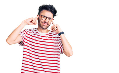 Fototapeta premium Young hispanic man wearing casual clothes covering ears with fingers with annoyed expression for the noise of loud music. deaf concept.