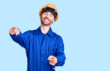 Young hispanic man wearing worker uniform pointing to you and the camera with fingers, smiling positive and cheerful