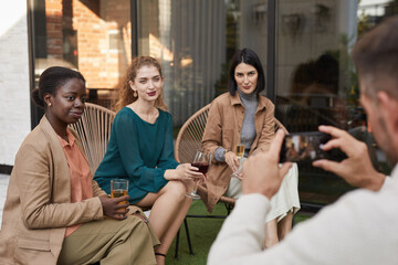 Portrait of three elegant women posing for photo and smiling at camera while enjoying outdoor party at terrace, copy space