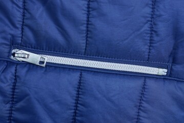 one white closed metal zip on the pocket on a blue synthetic fabric © butus