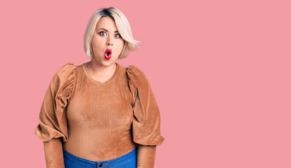 Young blonde plus size woman wearing casual sweater afraid and shocked with surprise expression, fear and excited face.