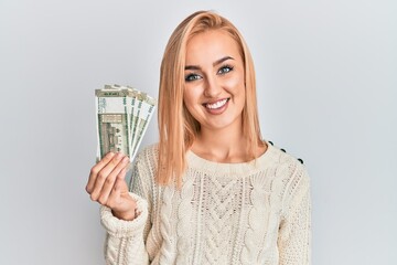 Beautiful caucasian woman holding 500 indian rupee banknotes looking positive and happy standing and smiling with a confident smile showing teeth