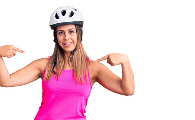 Young beautiful woman wearing bike helmet looking confident with smile on face, pointing oneself with fingers proud and happy.