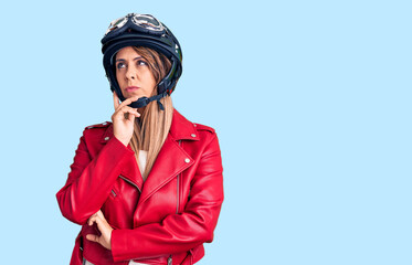 Young beautiful woman wearing motorcycle helmet serious face thinking about question with hand on chin, thoughtful about confusing idea