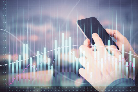 Double exposure of man's hands holding and using a digital device and forex graph drawing. Financial market concept.