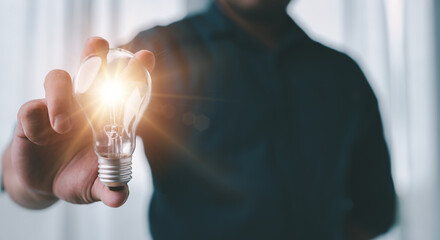 Idea innovation and inspiration concept.Hand of man holding illuminated light bulb, concept creativity with bulbs that shine glitter.Inspiration of ideas for sustainable business development.